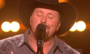 Singing man in a cowboy hat on stage.