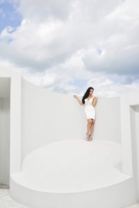 Woman in white dress against a light backdrop.