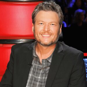 Smiling man in black jacket, red background.