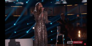 Woman singing in a sparkling silver dress.