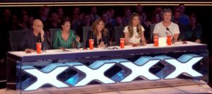 Five judges at illuminated talent show desk