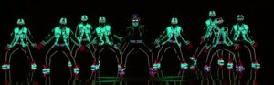 Dancers in neon costumes performing synchronized moves.