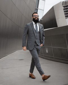 Man in stylish gray checkered suit walking.