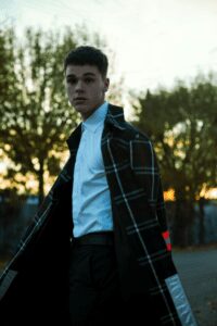 Young man in stylish coat against sunset.