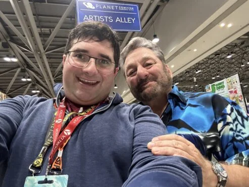 Two people posing at a convention.